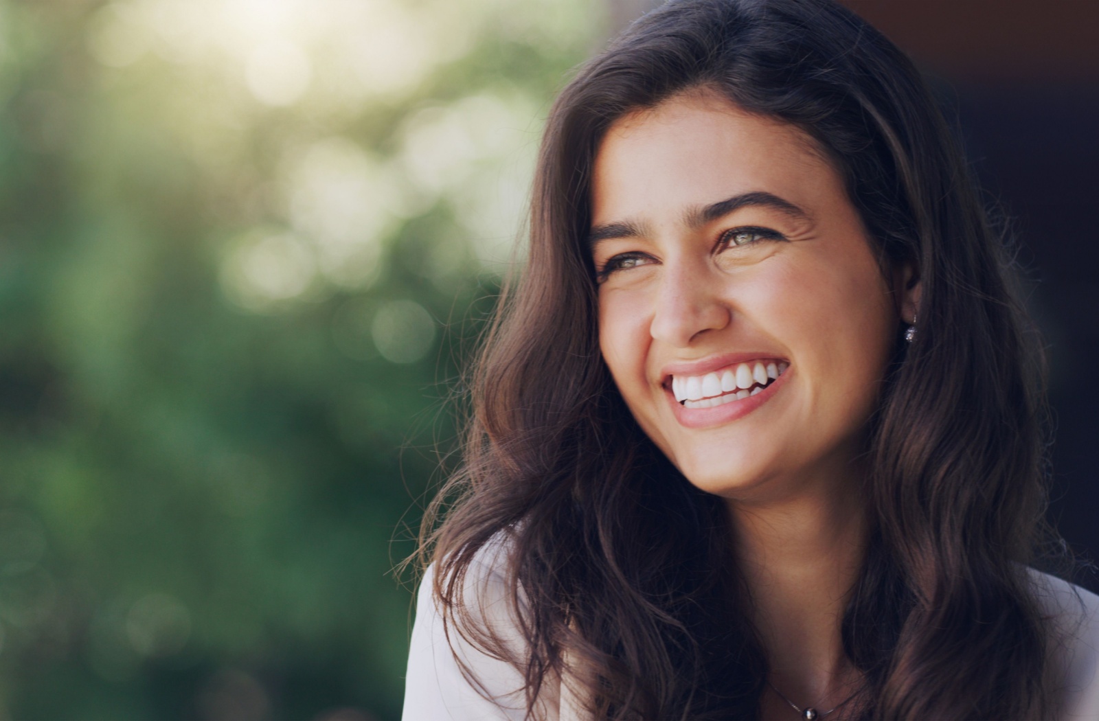 A person who is undergoing addiction recovery sitting outside smiling about their success with sobriety