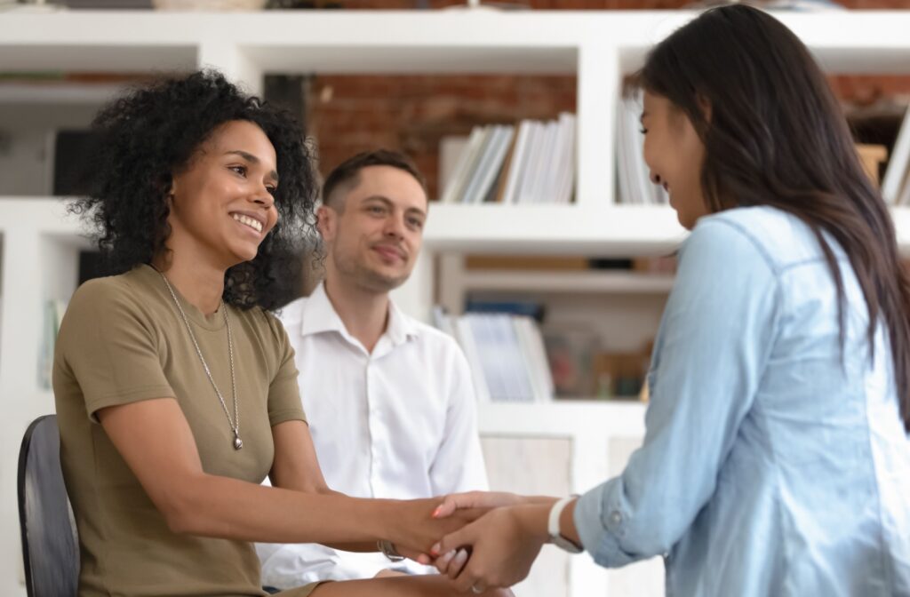 Group of patients in addiction recovery smiling and holding hands in a supportive setting.