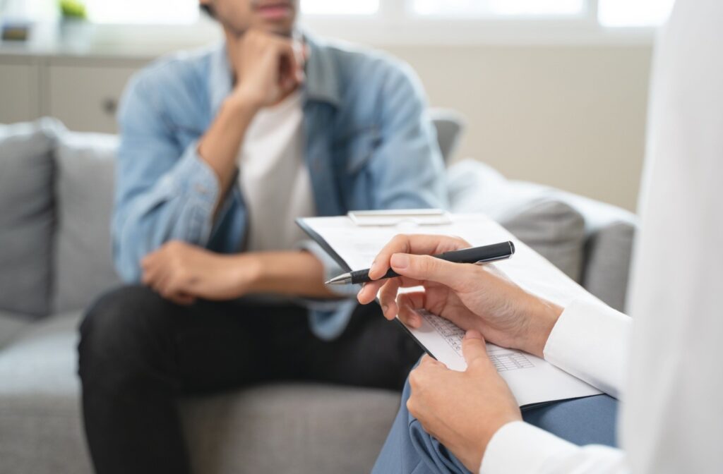 A person speaking with their therapist about substance use and mental health as their therapist takes notes.