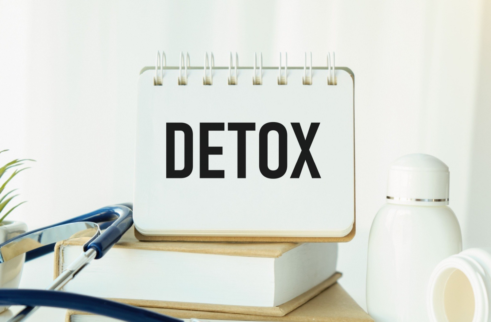Flip calendar displaying the word "DETOX" with a stethoscope and medication bottles on a desk.